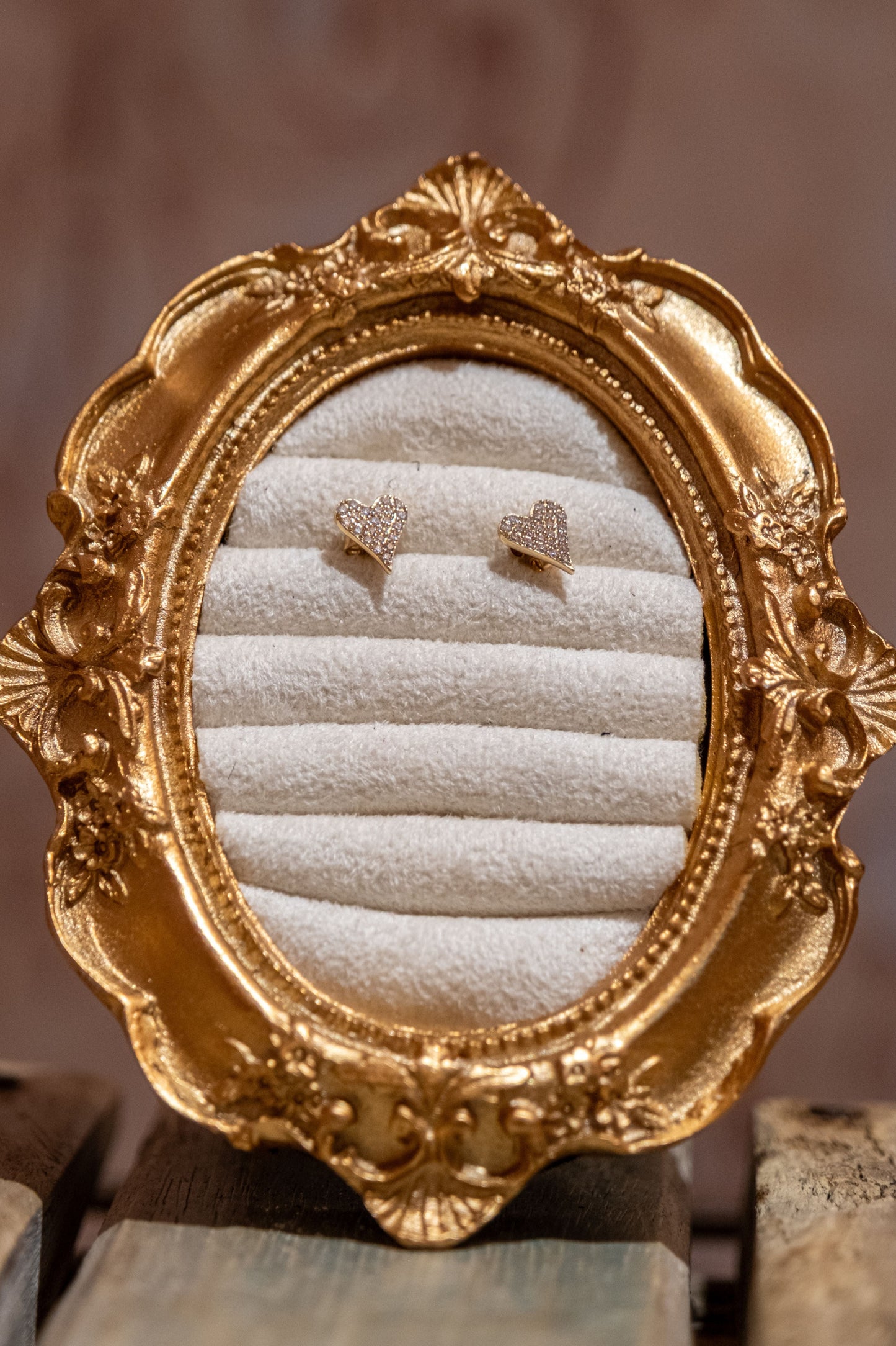 Decorative gold frame with jewelry on a wooden surface